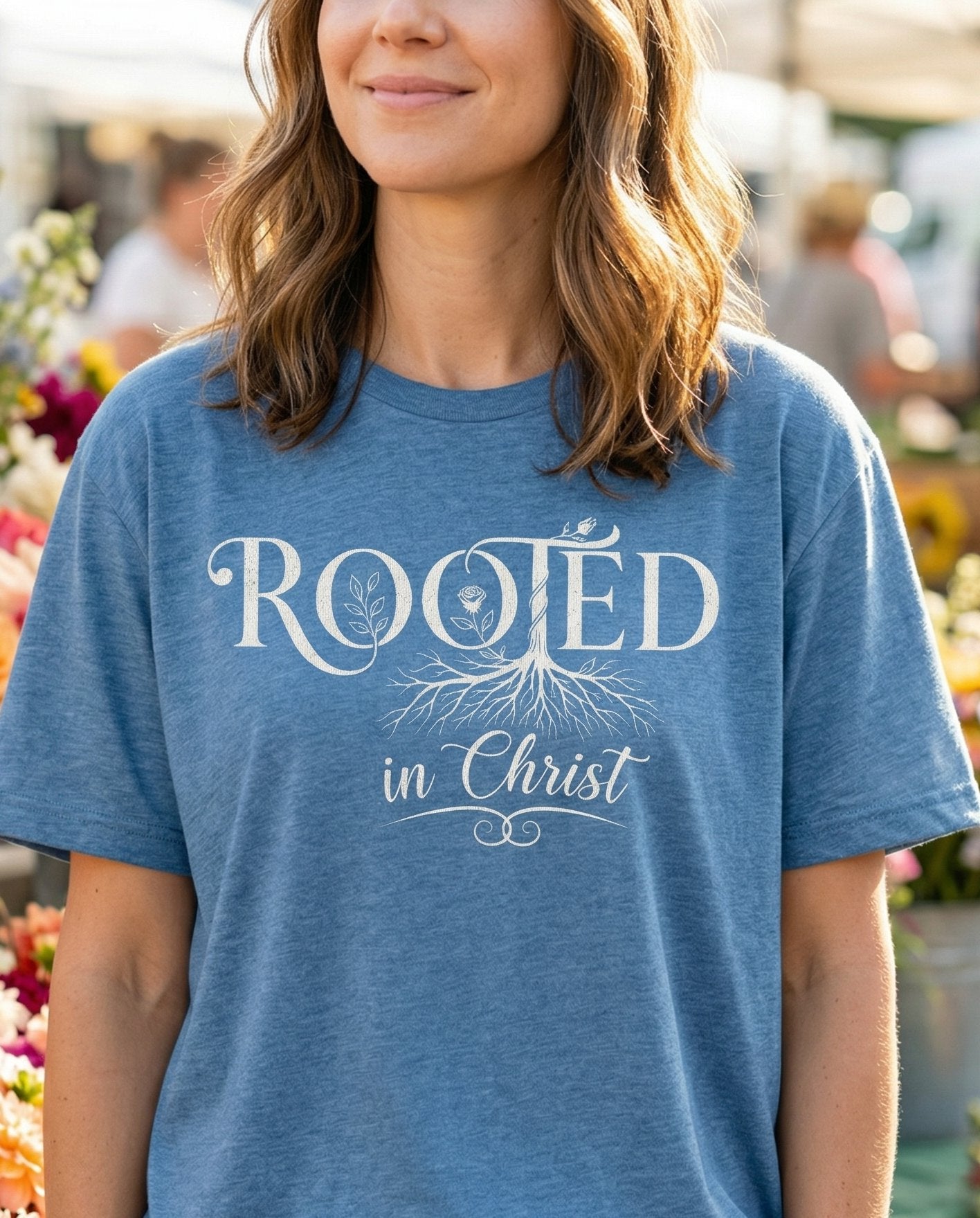 Rooted in Christ – Blue Jean women's Christian tee, lifestyle photo in farmers market – Elegant serif lettering 'Rooted in Christ' with a botanical tree and r – She Wears Faith