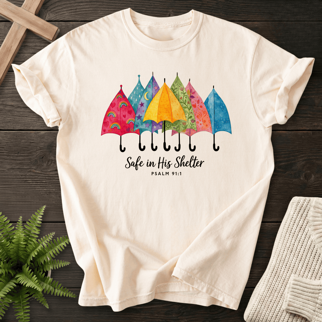 Ivory women's Christian t-shirt with watercolor umbrella design and "Safe in His Shelter," inspired by Psalm 91:1.