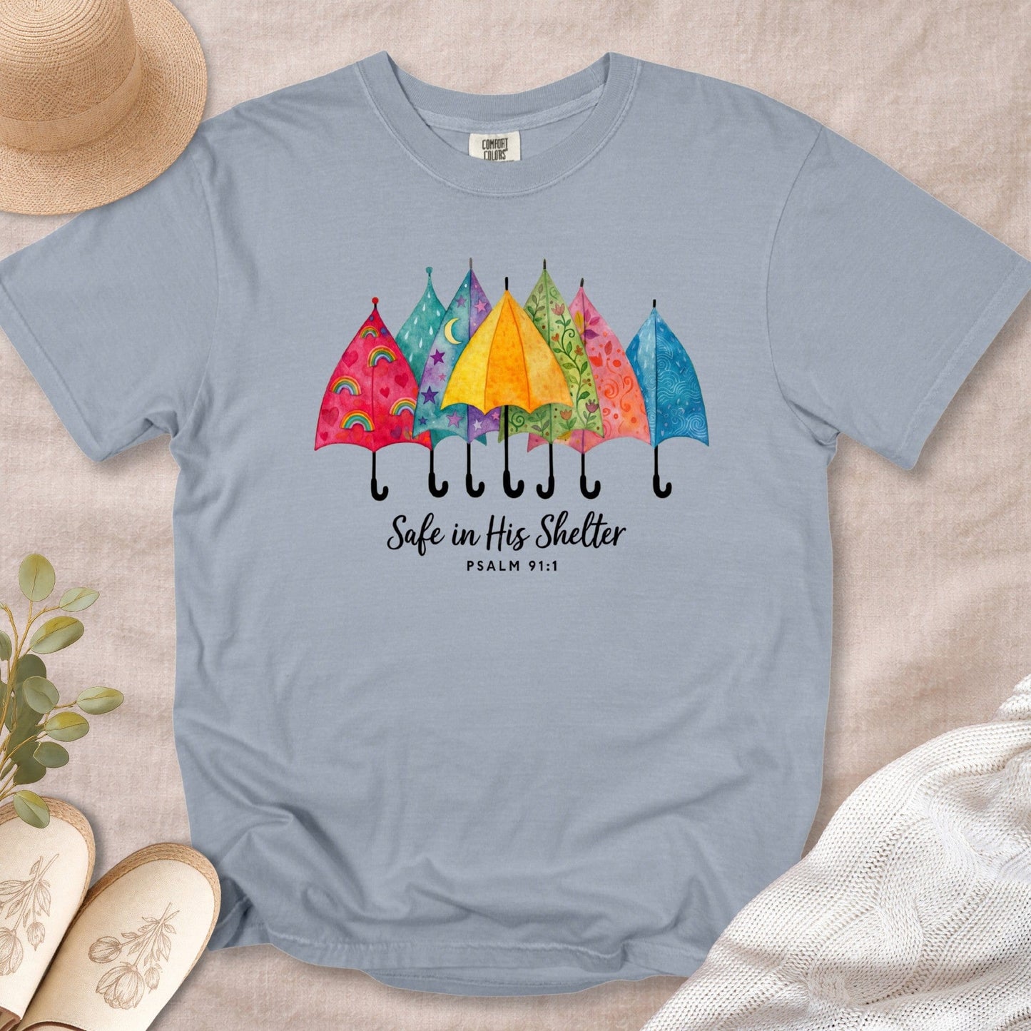 Granite Blue Comfort Colors 1717 tshirt with a bright umbrella graphic and Psalm 91:1. A comforting Christian women tee designed for modern US faith wear apparel.