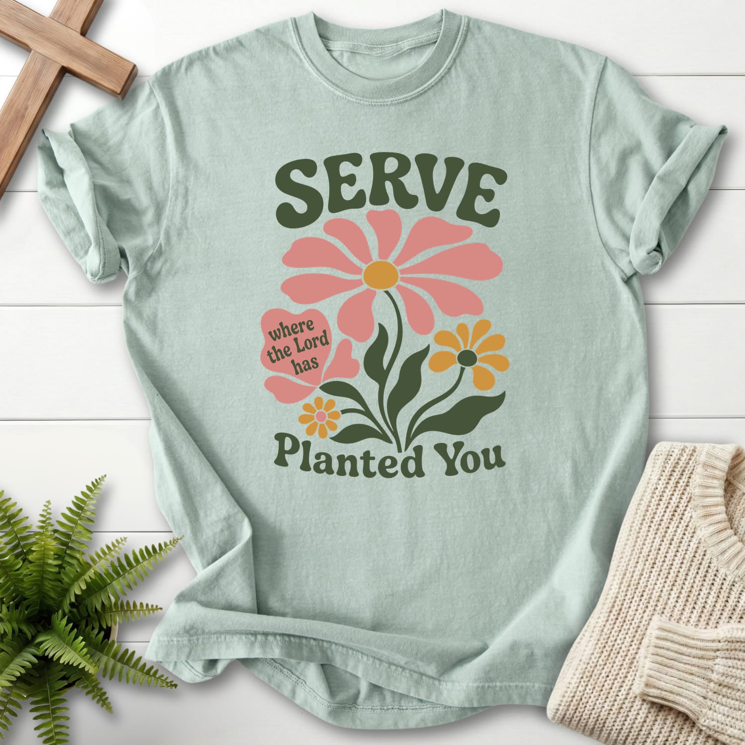 Flat lay of a Bay Christian shirt featuring floral line art with "Serve Where You Are Planted T-Shirt".