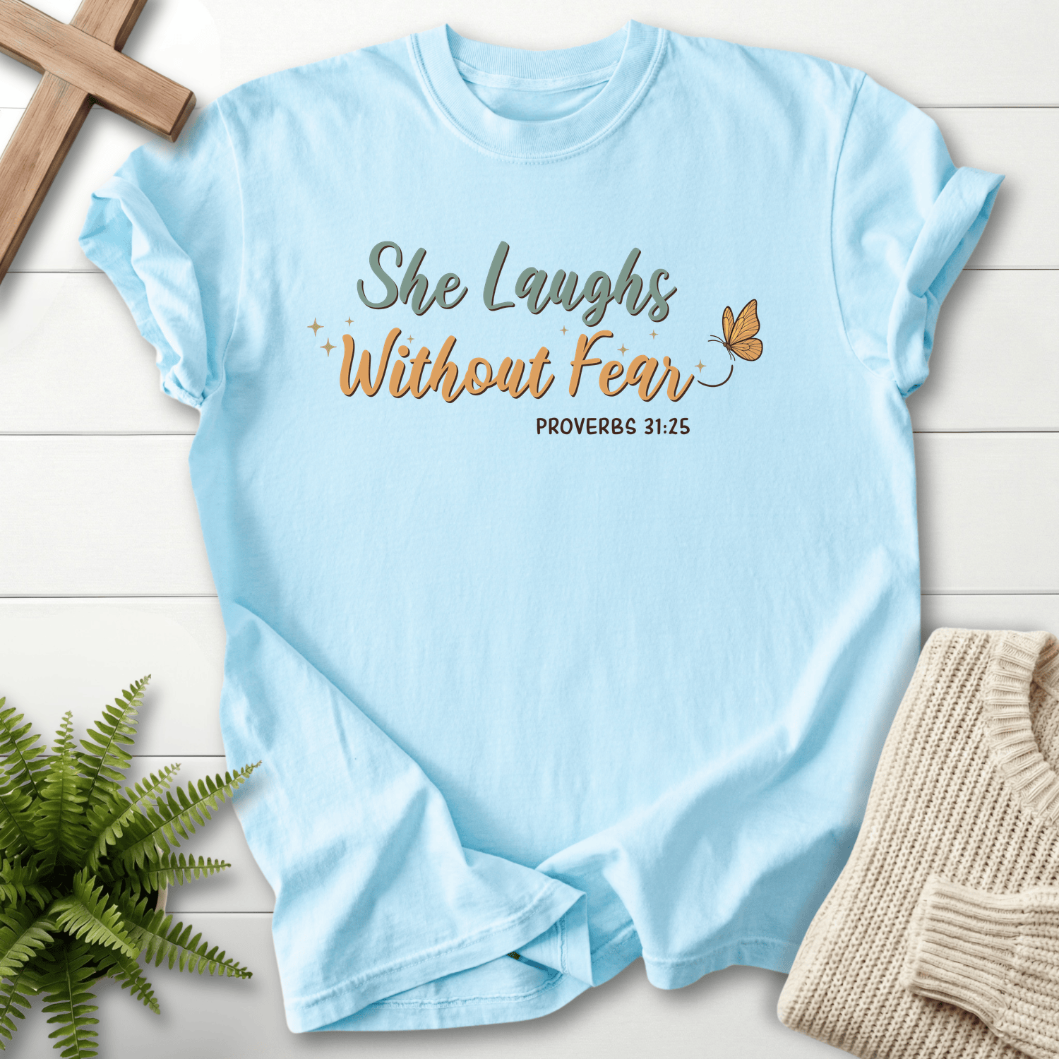 Chambray women's Bible verse tee with "She Laughs Without Fear" script and sparkle details, inspired by Proverbs 31:25.