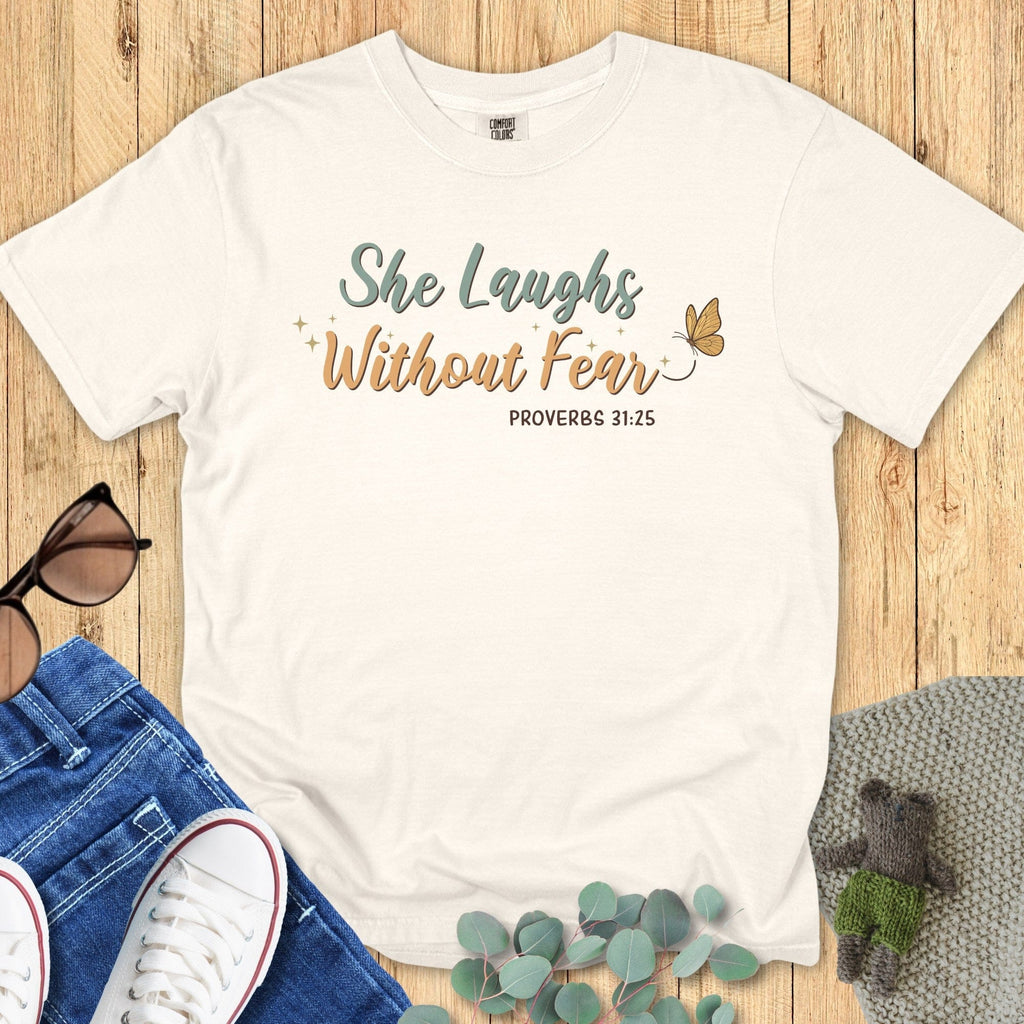 Flatlay of a Comfort Colors 1717 ivory “She Laughs Without Fear – Proverbs 31:25” t-shirt with gold and sage lettering and butterfly design. A minimalist women’s scripture tee — modern Christian shirt and beautiful faith-based apparel for women, ideal Christian mom gift.