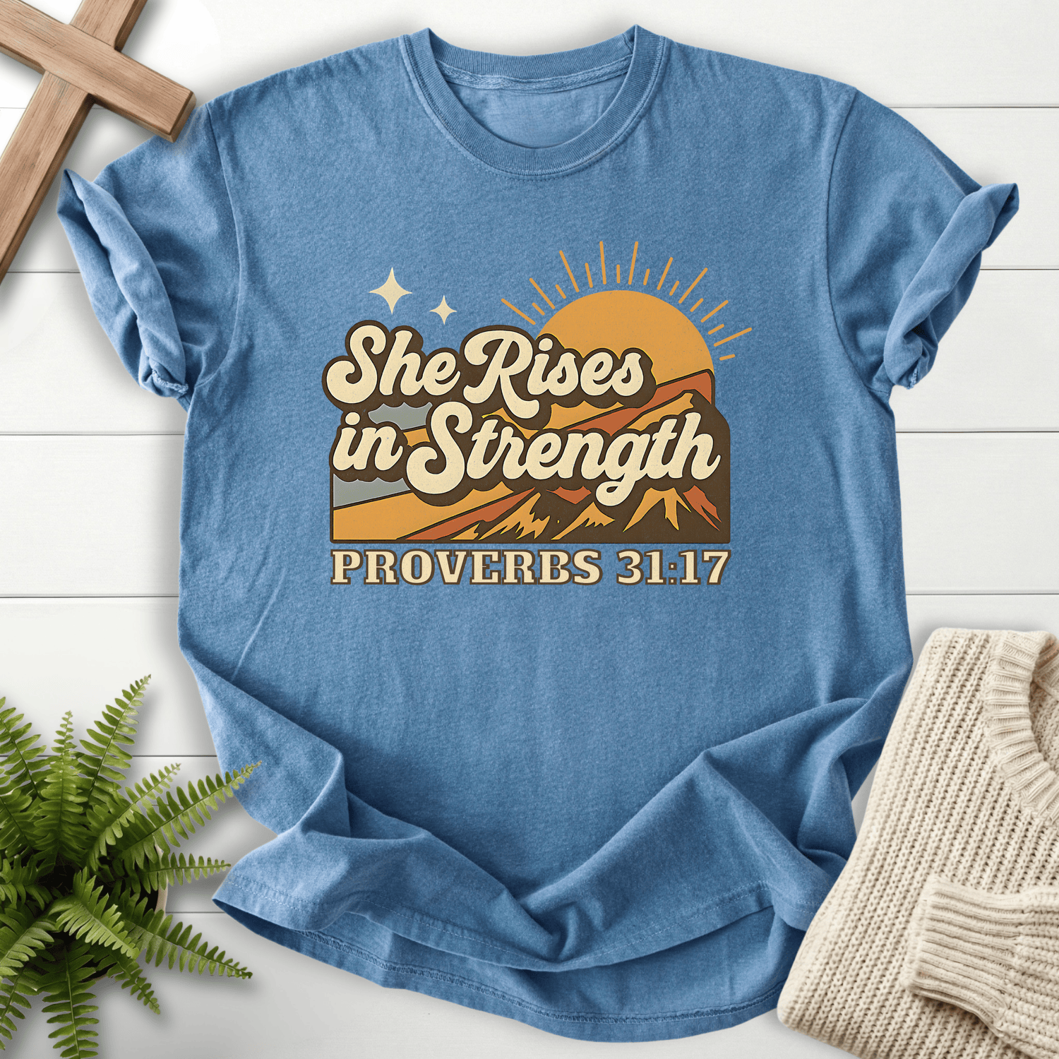 Blue Jean women's Christian t-shirt with retro mountain sunrise and "She Rises in Strength," inspired by Proverbs 31:17.