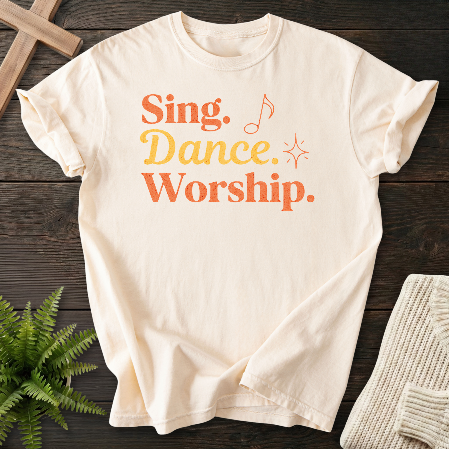 Ivory women's faith t-shirt with retro stacked "Sing, Dance, Worship" lettering and a music note.