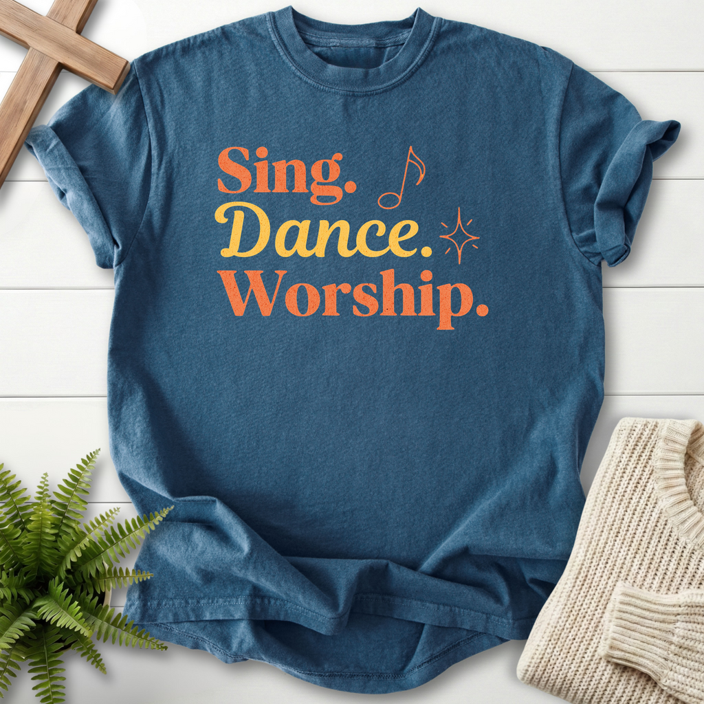 Midnight women's Christian t-shirt with bold "Sing, Dance, Worship" retro lettering in orange and gold.