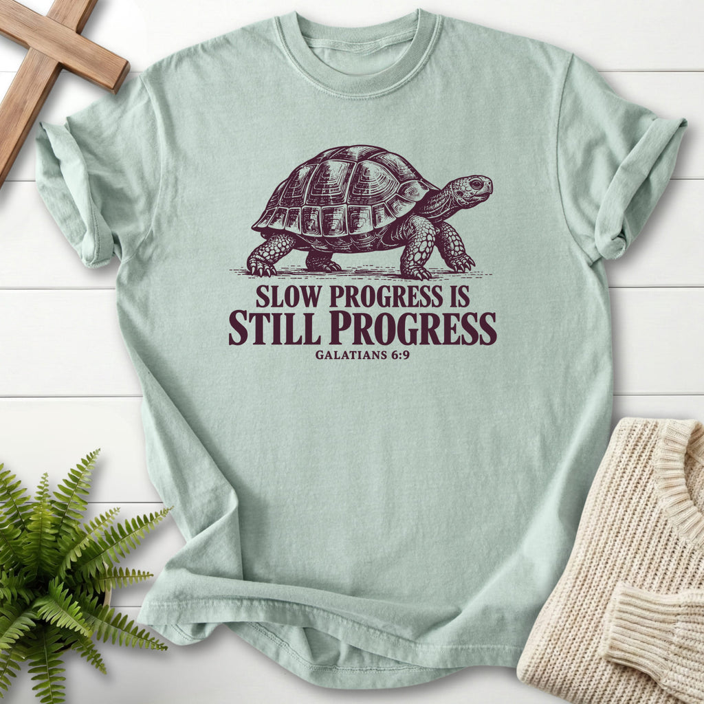 Flat lay of a Bay Bible verse tee featuring "Slow Progress Is Still Progress T-Shirt" Galatians 6:9.
