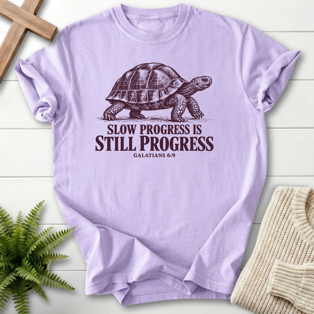 Flat lay of an Orchid Christian shirt featuring "Slow Progress Is Still Progress T-Shirt" Galatians 6:9.