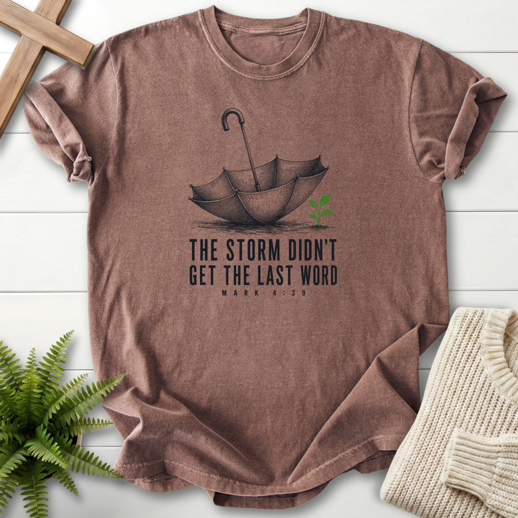Flat lay of an Espresso women's Christian tee featuring an engraved umbrella and seedling with "Storm Didn't Get the Last Word T-Shirt".