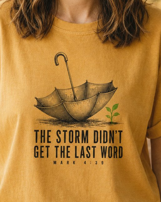 Storm Didn't Get the Last Word - Mustard women's Christian tee, lifestyle photo in nature trail - Inside-out umbrella with a green seedling growing beside it - Mark 4:39 - She Wears Faith