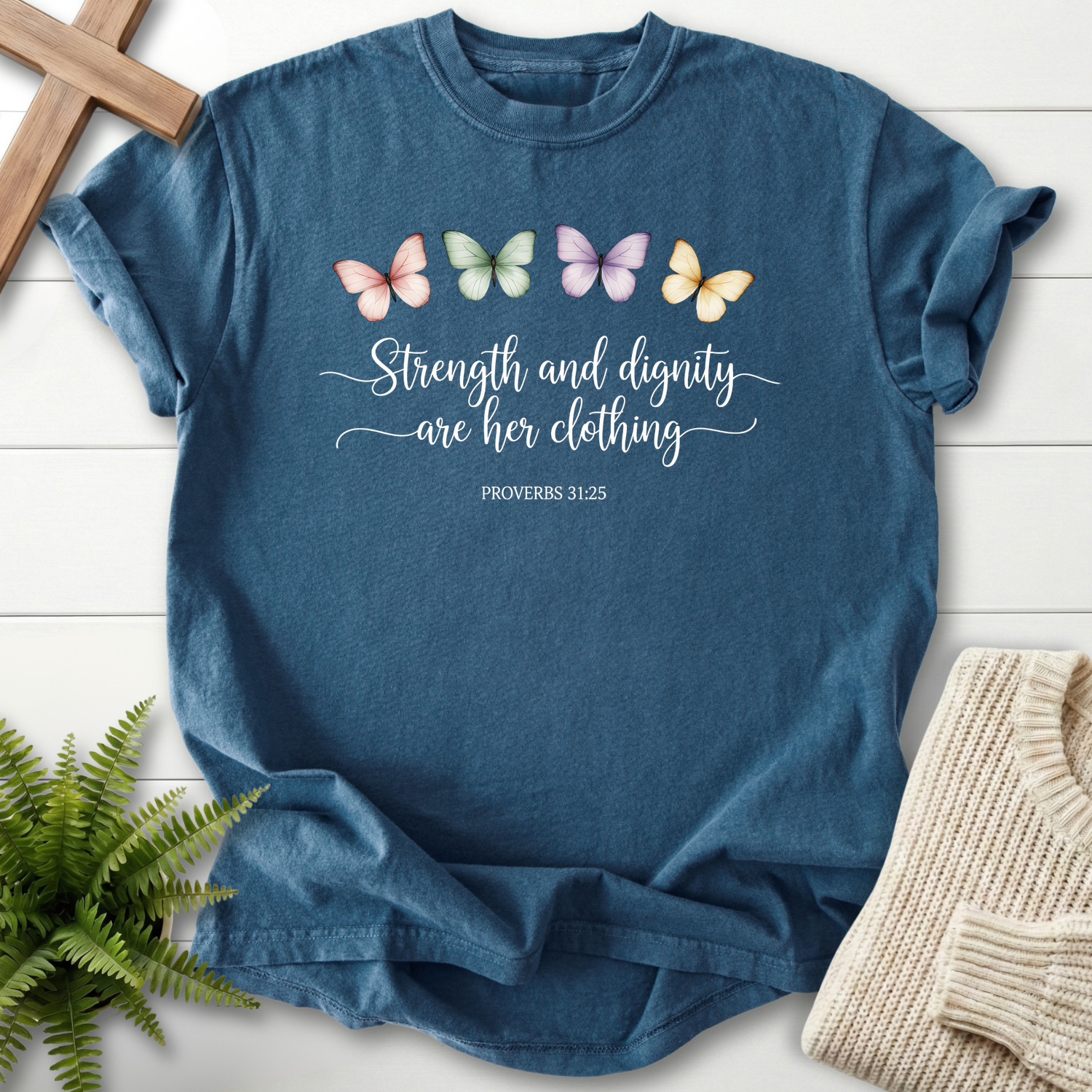 Midnight faith-based tee with a pastel butterfly row and Strength and Dignity Are Her Clothing, inspired by Proverbs 31:25.