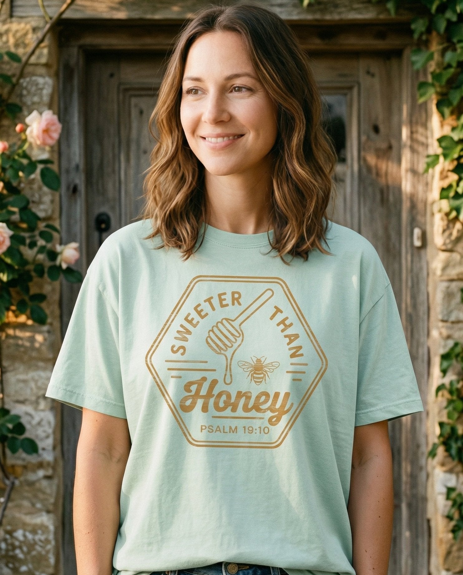 Sweeter Than Honey – Bay women's Christian tee, lifestyle photo in cottage doorway – Vintage hexagon badge design with 'Sweeter Than Honey' lettering surro – Psalm 19:10 – She Wears Faith