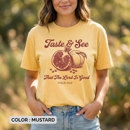 Woman wearing a mustard Comfort Colors 1717 Christian women tee featuring the “Taste & See That The Lord Is Good” Psalm 34:8 design with a vintage pomegranate illustration, photographed outdoors in soft natural light as part of modern US faith wear.
