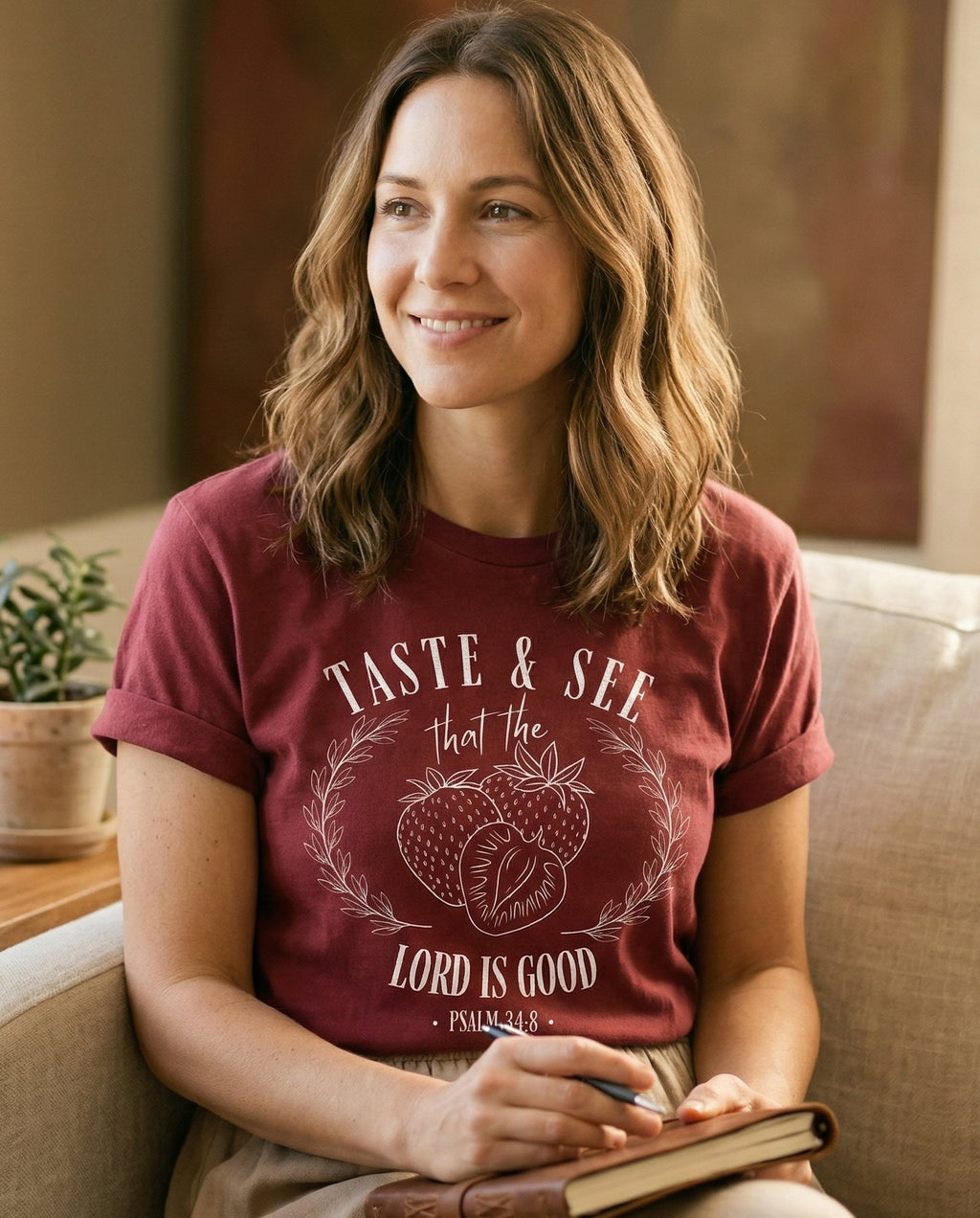 Taste & See Strawberry – Chili women's Christian tee, lifestyle photo in cozy living room – Circular wreath design with 'Taste & See that the Lord Is Good' letter – Psalm 34:8 – She Wears Faith