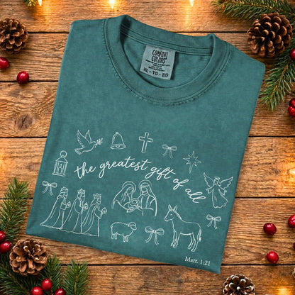 Folded blue spruce Comfort Colors 1717 Christian women tee with hand-drawn Nativity illustrations and scripture Matthew 1:21, vintage-inspired Christian tshirt for women, US faith wear flat lay.