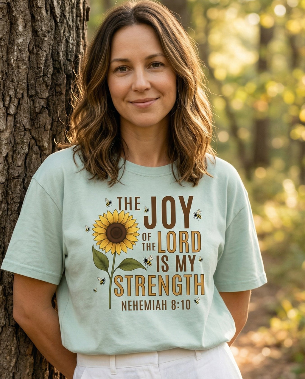 Joy of the Lord – Bay women's Christian tee, lifestyle photo in nature trail – Bold 'The Joy of the Lord Is My Strength' lettering alongside a tall s – Nehemiah 8:10 – She Wears Faith