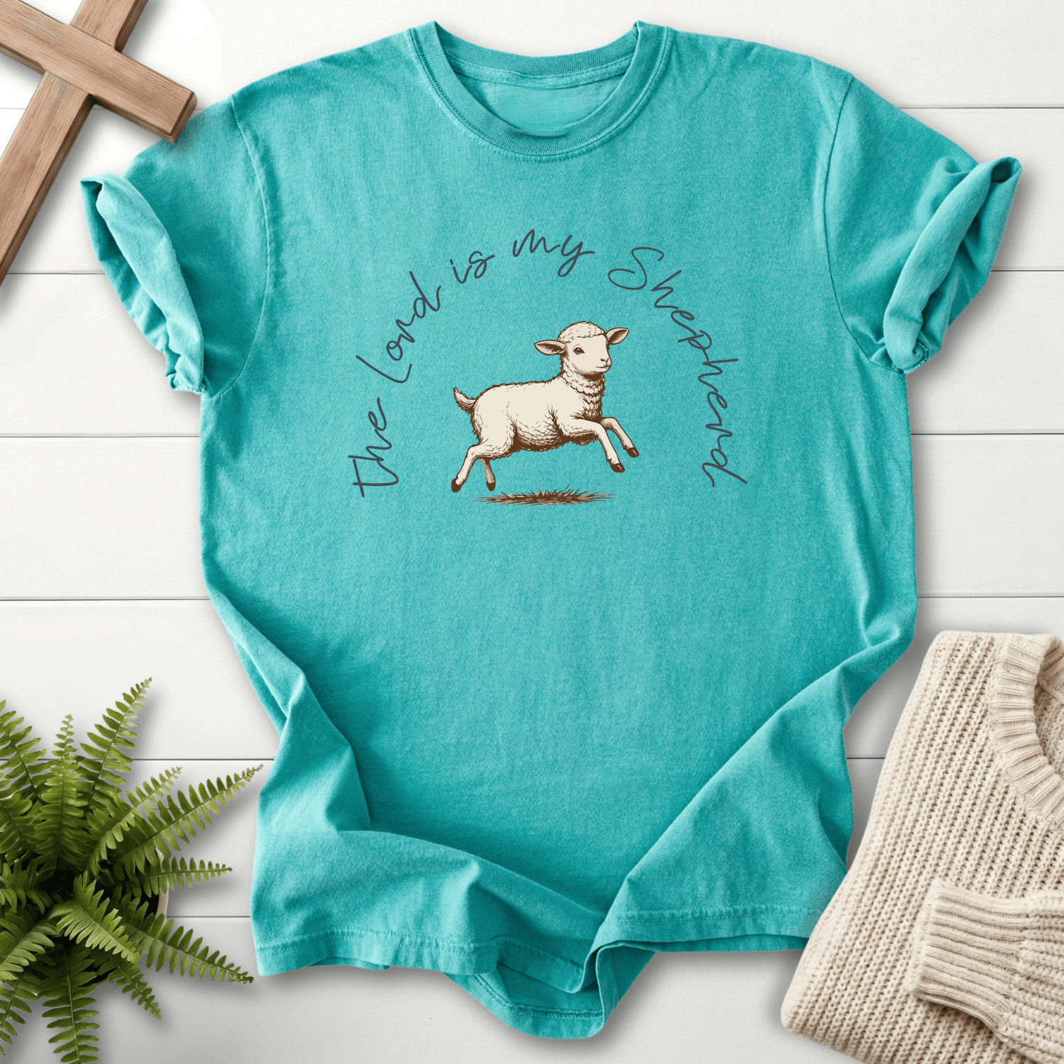 Seafoam faith-based tee with a hand-drawn leaping lamb illustration and arched cursive script, Comfort Colors 1717, inspired by Psalm 23.