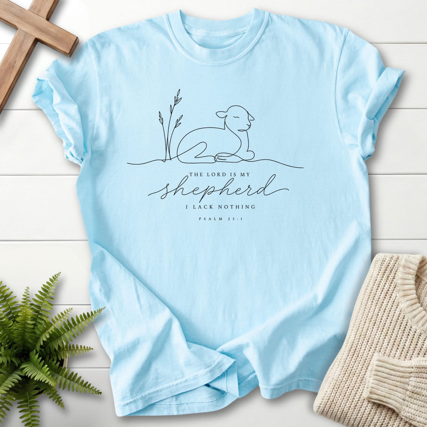 Flat lay of a Chambray Bible verse tee featuring minimalist design with "The Lord is my Shepherd Line Art T-Shirt" Psalm 23:1.