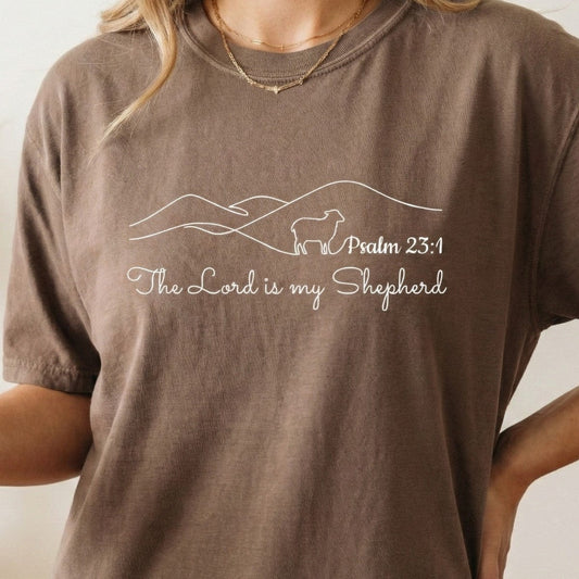 Woman wearing an Espresso Brown Comfort Colors 1717 tshirt with a minimalist Psalm 23:1 design. Lifestyle photography of a Christian women tee layered with gold jewelry, showcasing trendy US faith wear.