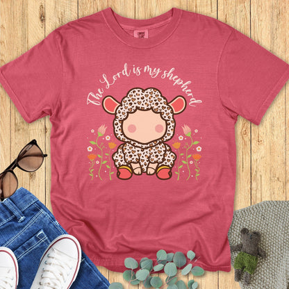 Flatlay of a Comfort Colors 1717 crimson “The Lord Is My Shepherd” t-shirt featuring an adorable cartoon lamb surrounded by flowers. A sweet women’s scripture tee and uplifting faith-based apparel for women — perfect Christian mom gift idea.