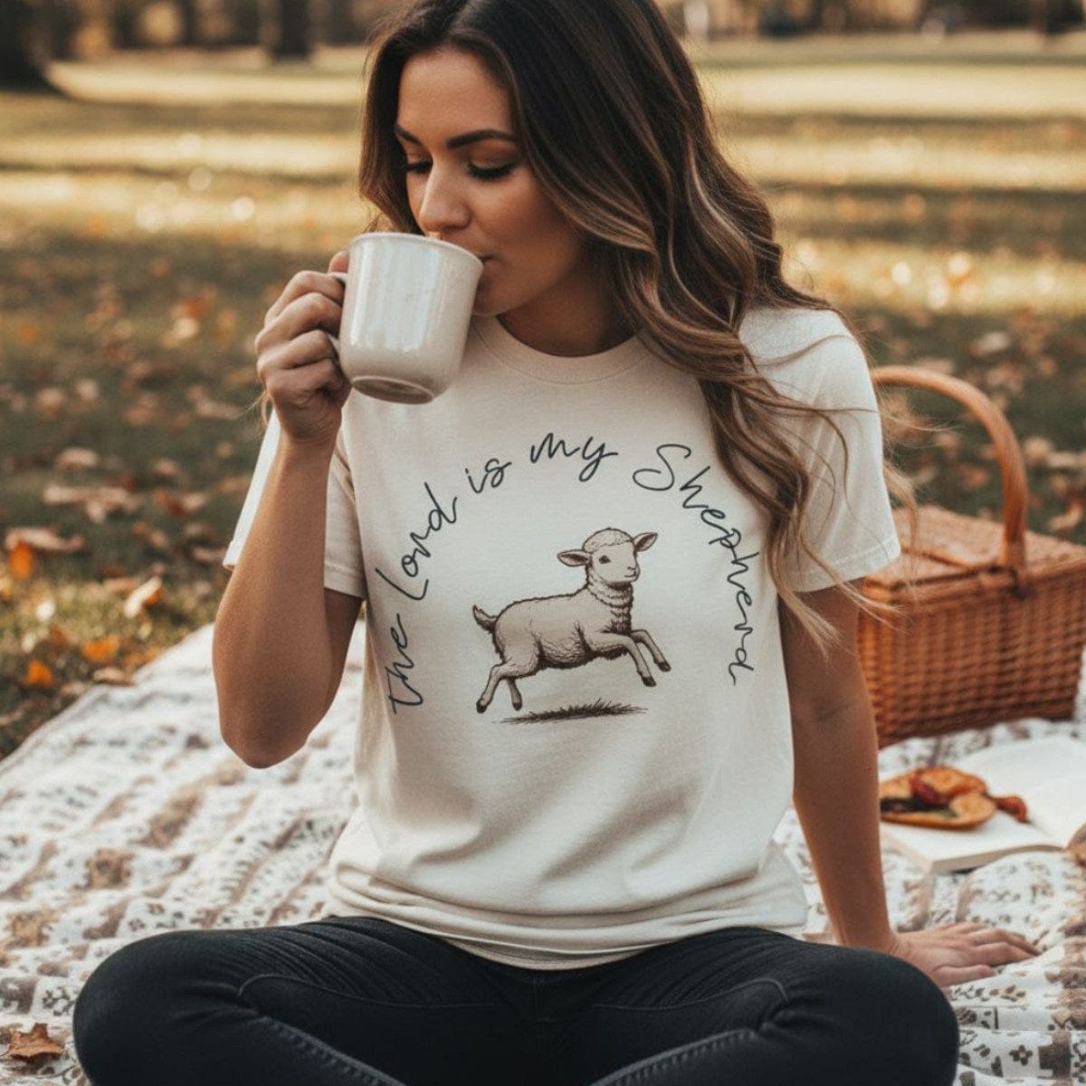 Woman enjoying coffee outdoors while wearing a Comfort Colors 1717 ivory “The Lord Is My Shepherd” t-shirt. A cozy faith-based apparel for women design inspired by Psalm 23.