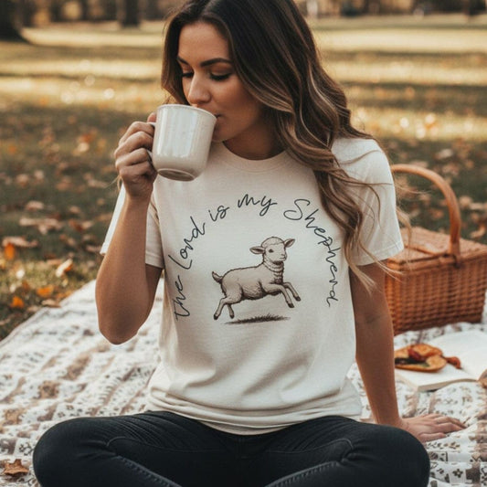 Woman enjoying coffee outdoors while wearing a Comfort Colors 1717 ivory “The Lord Is My Shepherd” t-shirt. A cozy faith-based apparel for women design inspired by Psalm 23.