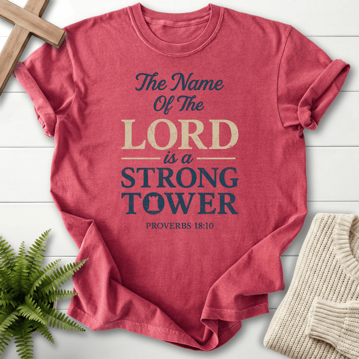 Crimson faith-based tee with layered Strong Tower lettering, a tower icon, and distressed Proverbs 18:10 text, inspired by Proverbs 18:10.