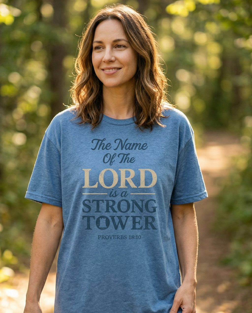 Name of the Lord – Blue Jean women's Christian tee, lifestyle photo in nature trail – Distressed layered typography with 'The Name of the Lord Is a Strong T – Proverbs 18:10 – She Wears Faith