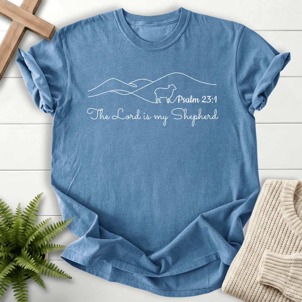 Blue Jean faith-based tee with a minimalist mountain ridge, lamb silhouette, and The Lord Is My Shepherd script, inspired by Psalm 23:1.