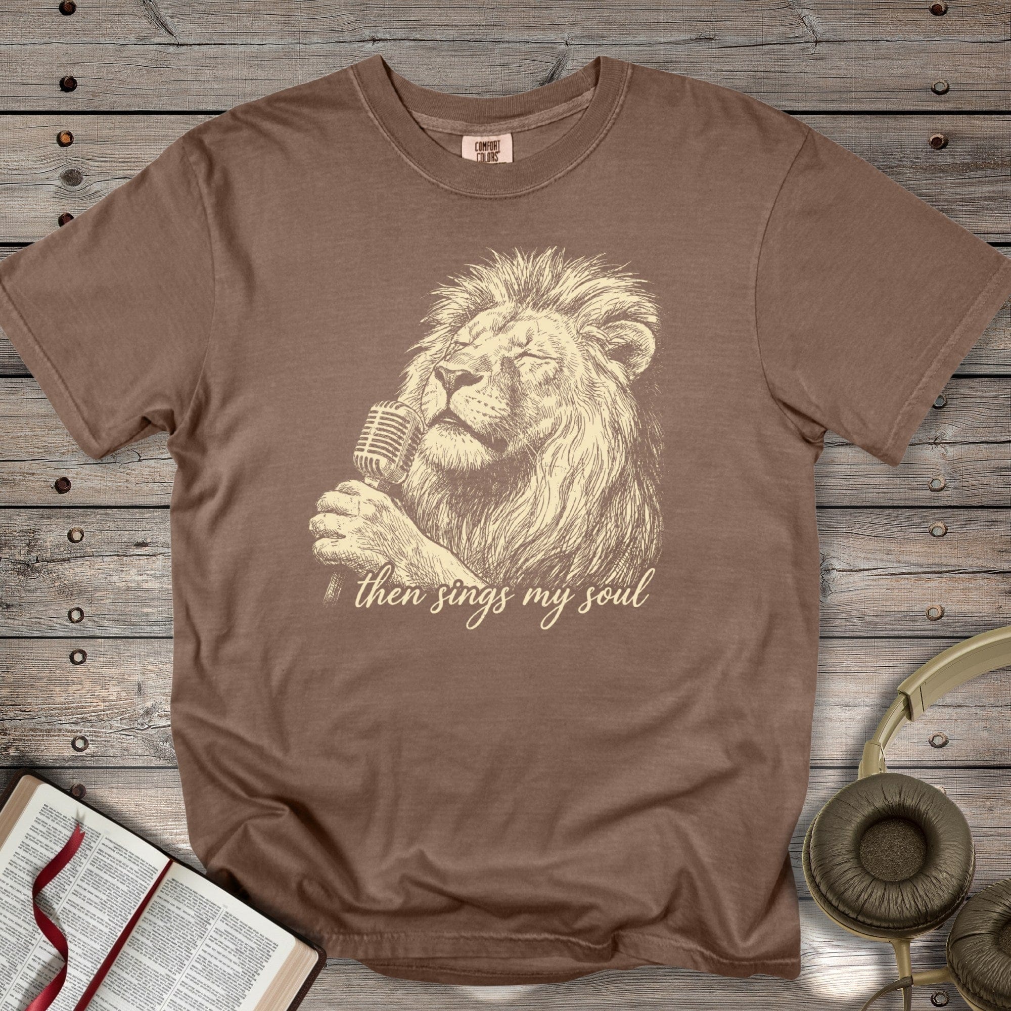 Espresso Brown Comfort Colors 1717 tshirt with a cream-colored lion graphic and worship lyrics. Vintage-inspired Christian women tee styled with worship accessories, ideal for US faith wear collections.