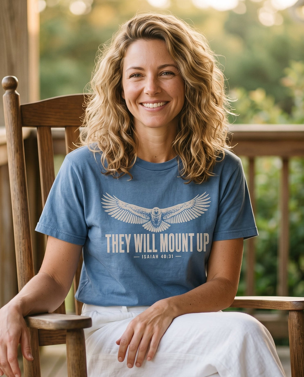 They Will Mount Up Eagle – Blue Jean women's Christian tee, lifestyle photo in sunny porch – A tan distressed illustration of an eagle soaring with wings fully spr – Isaiah 40:31 – She Wears Faith