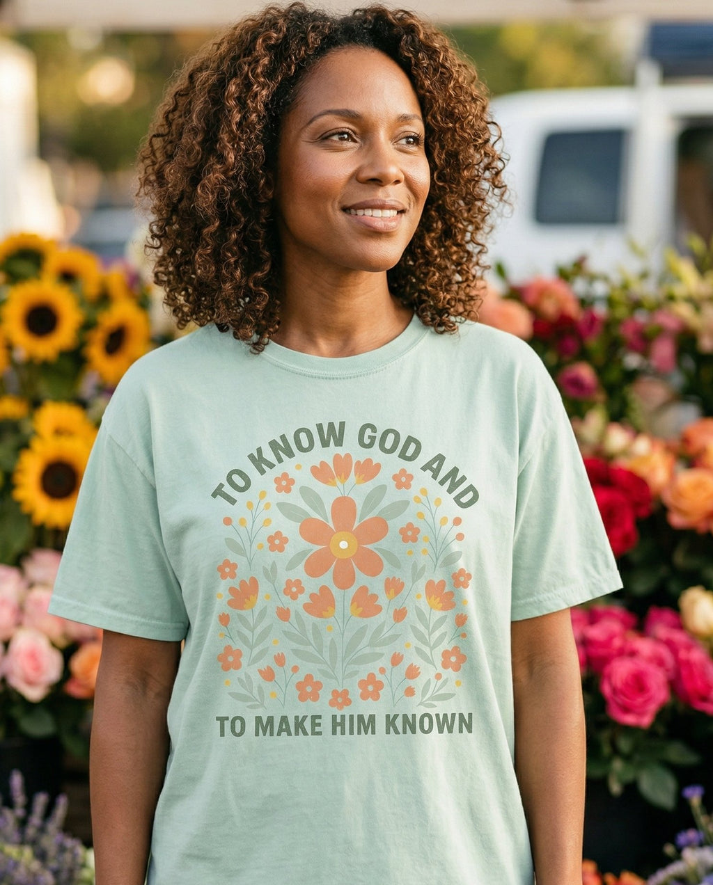 To Know God – Bay women's Christian tee, lifestyle photo in farmers market – Arched boho floral design with 'To Know God And To Make Him Known' tex – She Wears Faith