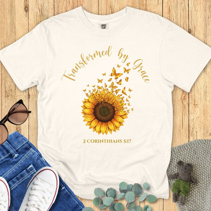 Comfort Colors 1717 Christian women t-shirt in ivory flat lay. Christian sunflower graphic with butterflies and scripture text “Transformed by Grace – 2 Corinthians 5:17