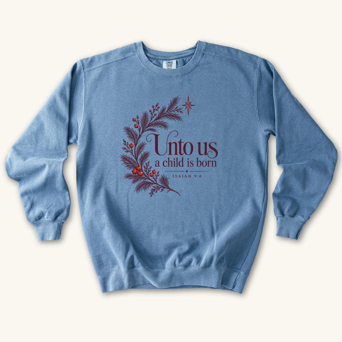 Blue Jean Christian Christmas sweatshirt with Unto Us a Child Is Born lettering, evergreen branches, red berries, a star and Isaiah 9:6.