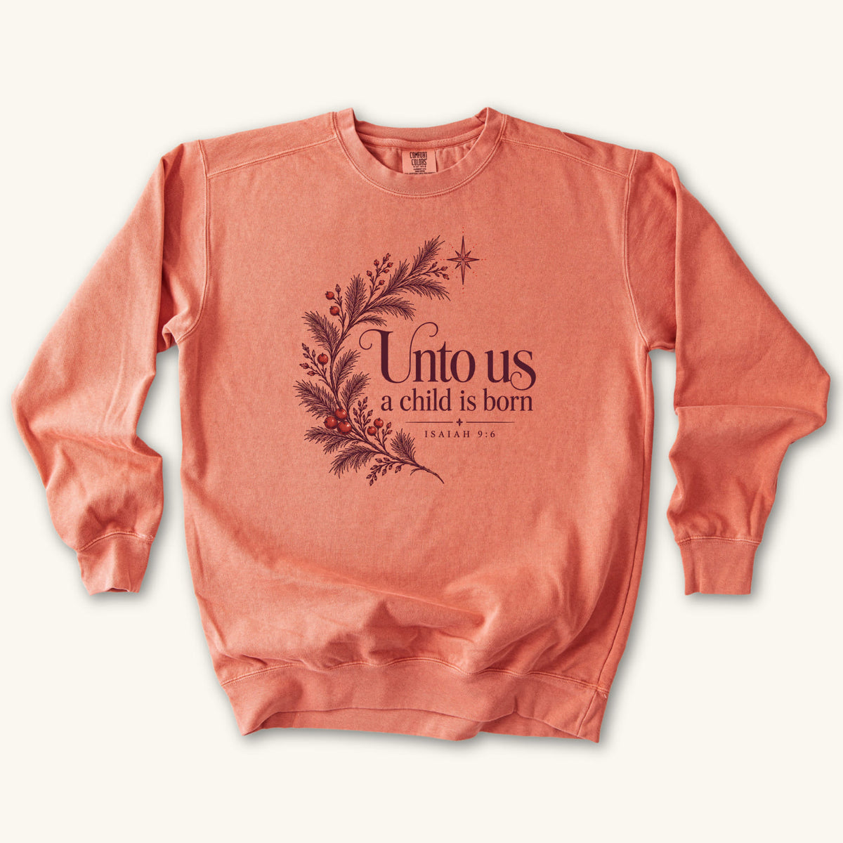Terracotta Christian Christmas sweatshirt with Unto Us a Child Is Born lettering, evergreen branches, red berries, a star and Isaiah 9:6.