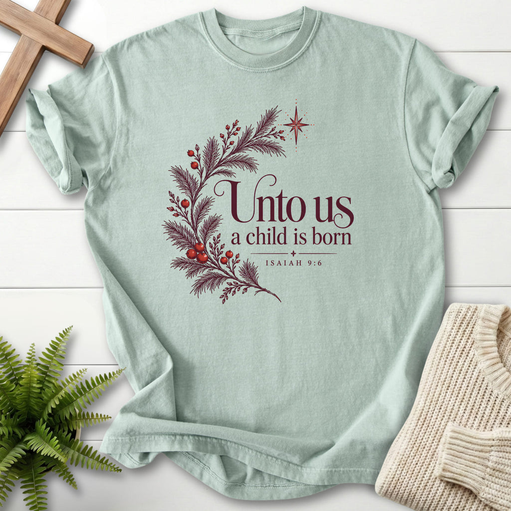 Bay color option for the Unto Us a Child Is Born tee with evergreen branches, red berries and a star with "Unto Us a Child Is Born T-Shirt" for women's faith apparel.