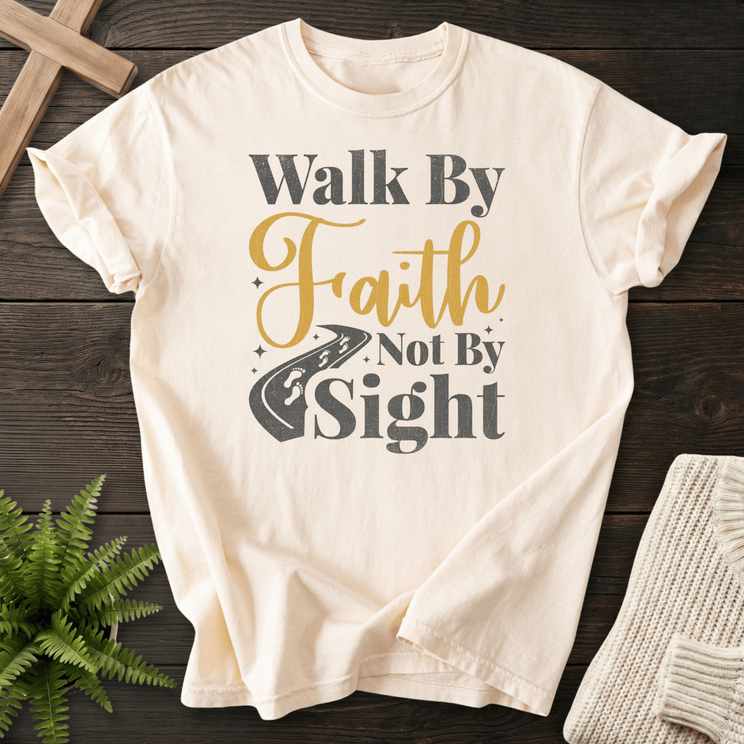Ivory Christian t-shirt for women with gold and gray Walk By Faith Not By Sight lettering and a road graphic, inspired by 2 Corinthians 5:7.