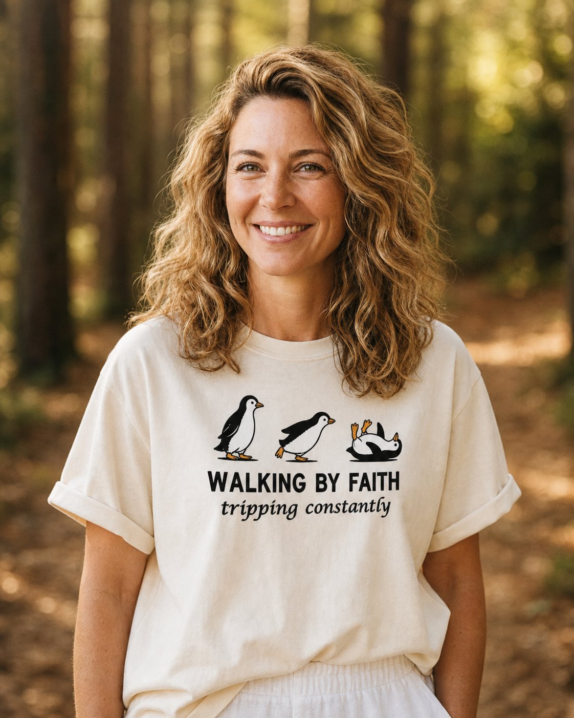 Walking By Faith – Ivory women's Christian tee, lifestyle photo in nature trail – Humorous cartoon penguins with hand-lettered slogan – She Wears Faith