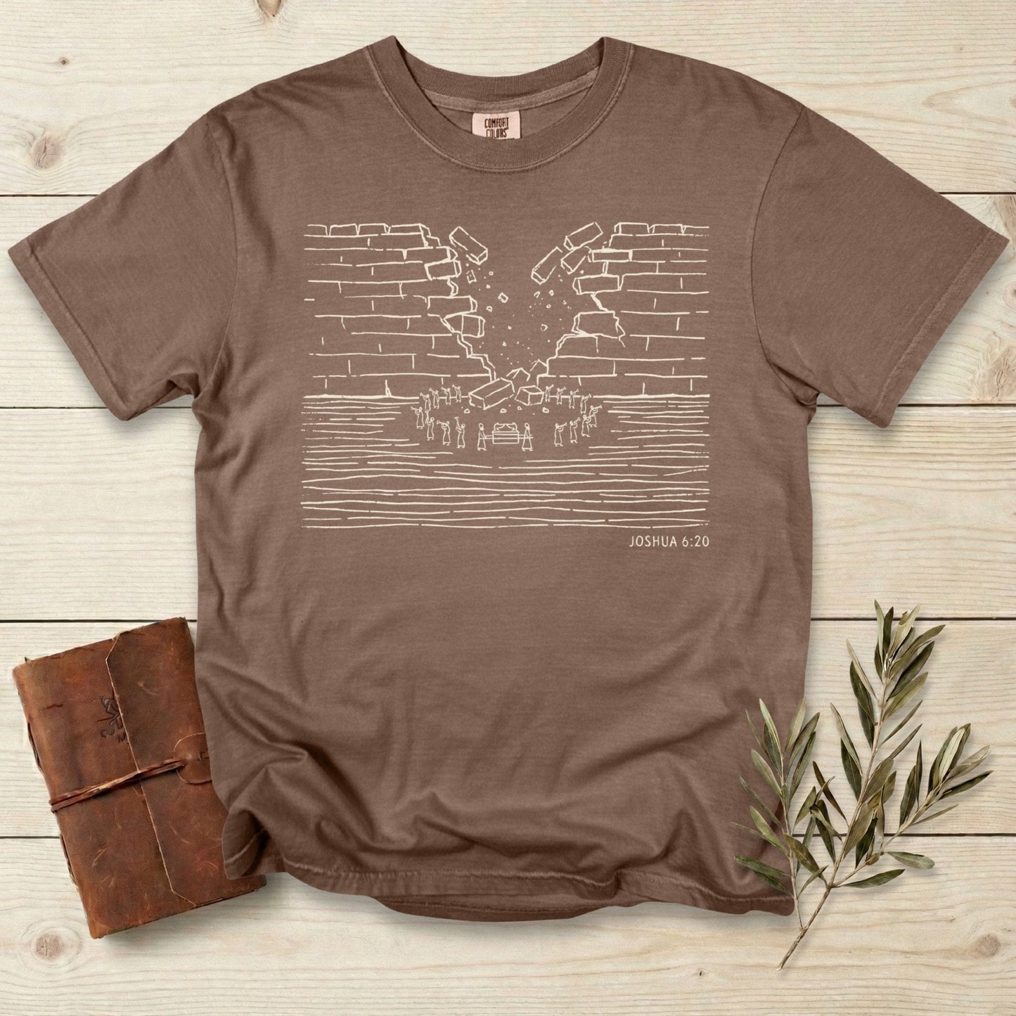 Comfort Colors 1717 espresso brown Christian women’s T-shirt with a clean line-art illustration of the fall of Jericho from Joshua 6:20. A soft, garment-dyed faith tee designed for women who love modern scripture graphics and US faith wear.