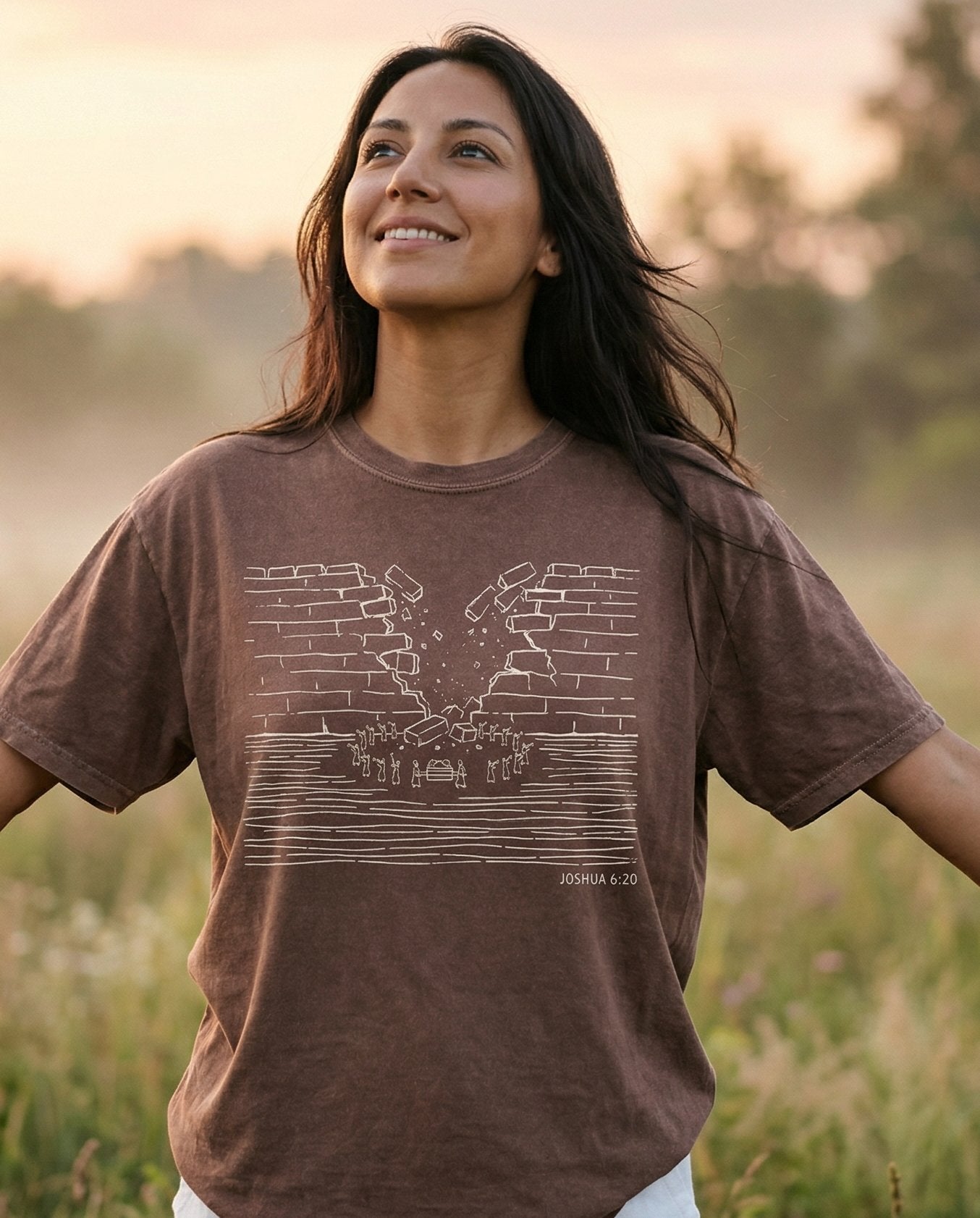Walls of Jericho – Espresso women's Christian tee, lifestyle photo in wildflower meadow at sunrise – Minimalist line-art sketch of the walls of Jericho crumbling apart wit – Joshua 6:20 – She Wears Faith