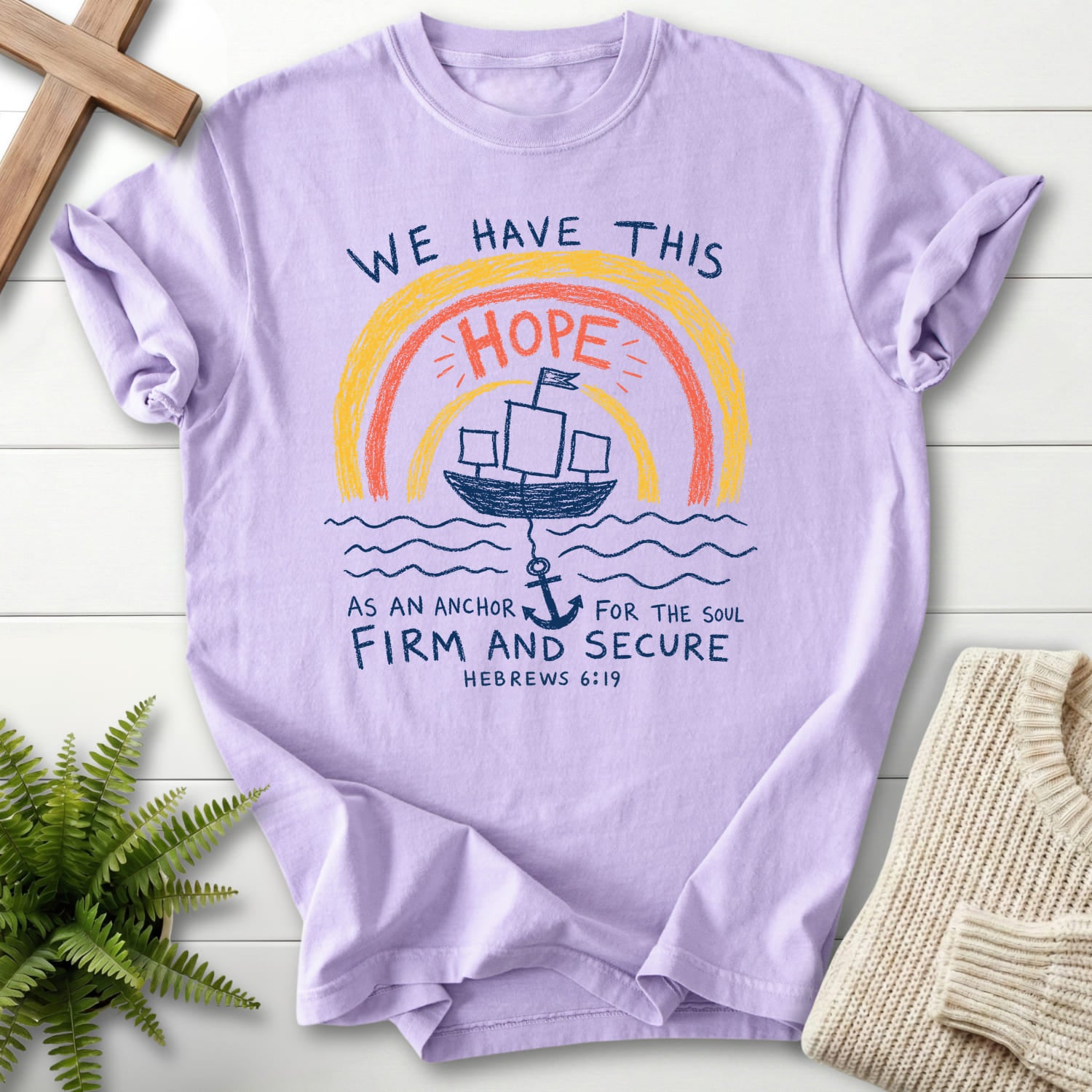 Flat lay of an Orchid Scripture shirt featuring "WE HAYE THIS T-Shirt" Hebrews 6:19.