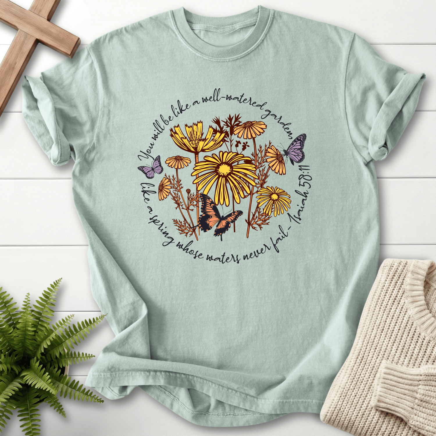 Bay Christian t-shirt for women with a circular daisy and butterfly design, inspired by Isaiah 58:11.
