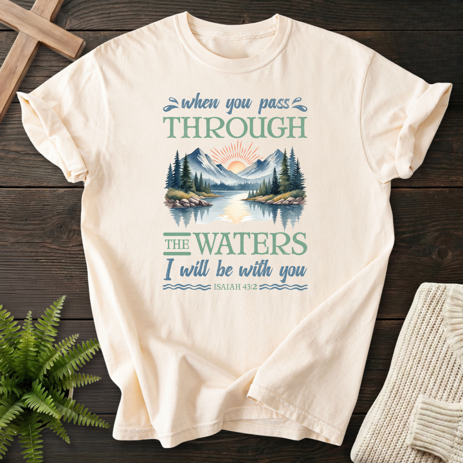 Ivory faith-based tee with a serene mountain and water scene, inspired by Isaiah 43:2.