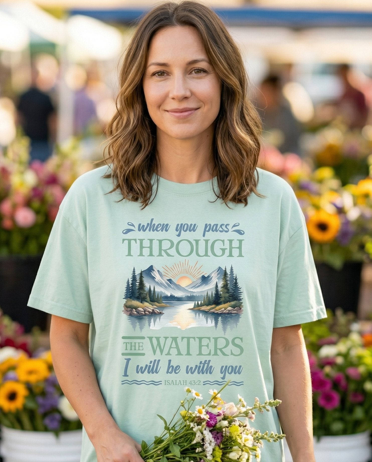 Through The Waters – Bay women's Christian tee, lifestyle photo in farmers market – Serene mountain lake landscape with a sunrise framed between pine tree – Isaiah 43:2 – She Wears Faith