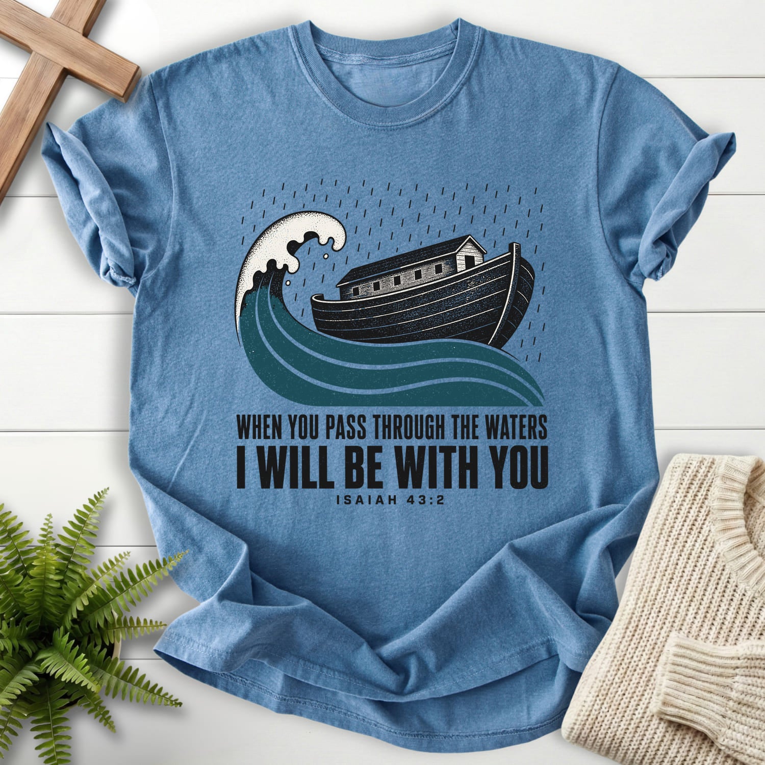 Flatlay of a Blue Jean Christian graphic tee with "When You Pass Through The Waters T-Shirt" Isaiah 43:2.