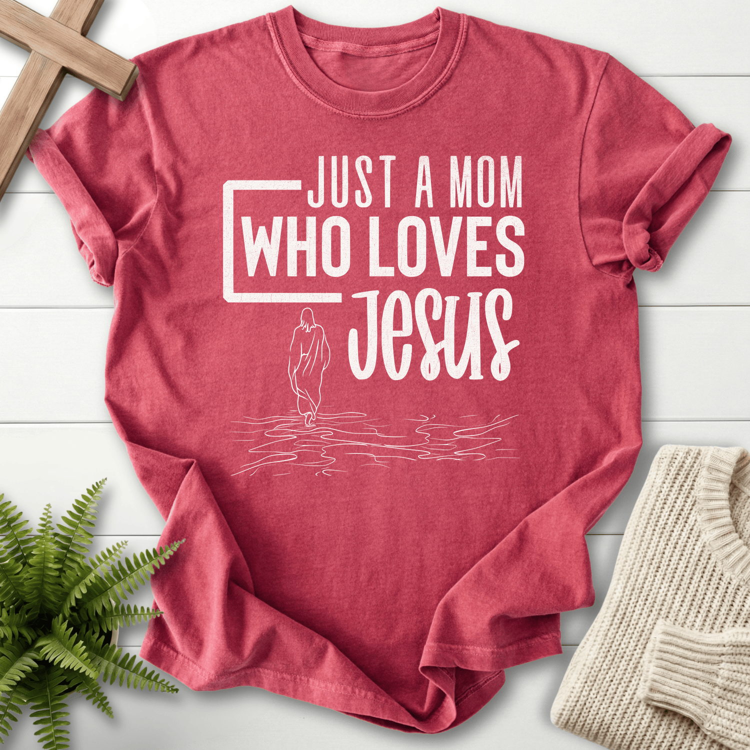 Crimson garment-dyed Christian t-shirt with 'Just a Mom Who Loves Jesus' and walking figure illustration.
