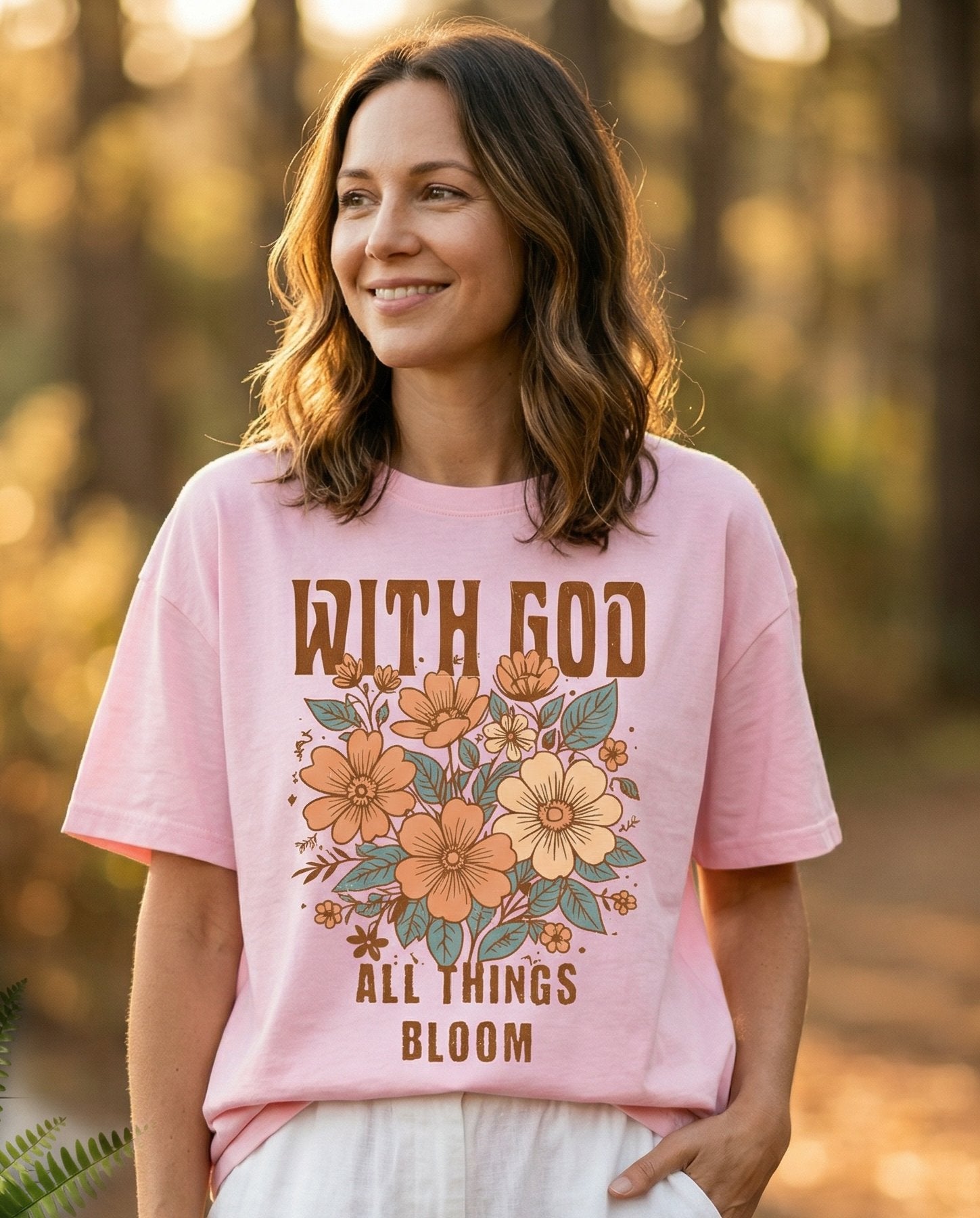 All Things Bloom – Blossom women's Christian tee, lifestyle photo in nature trail – Retro-style floral bouquet in warm earthy tones with bold 'With God Al – She Wears Faith
