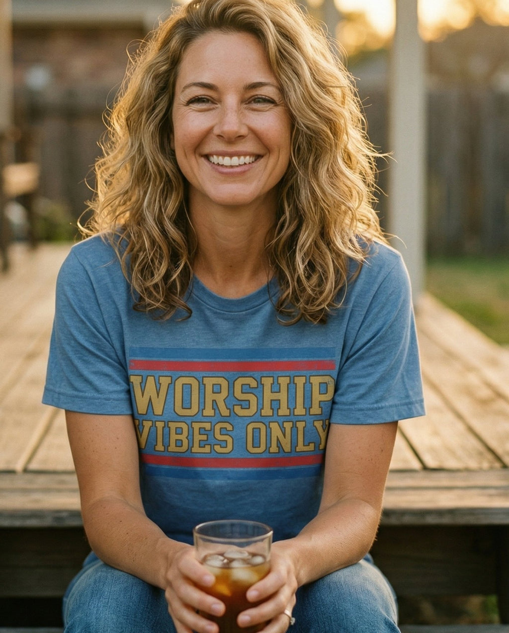 Worship Vibes Only – Blue Jean women's Christian tee, lifestyle photo in sunny porch – Vintage collegiate-style block lettering 'Worship Vibes Only' in gold  – She Wears Faith