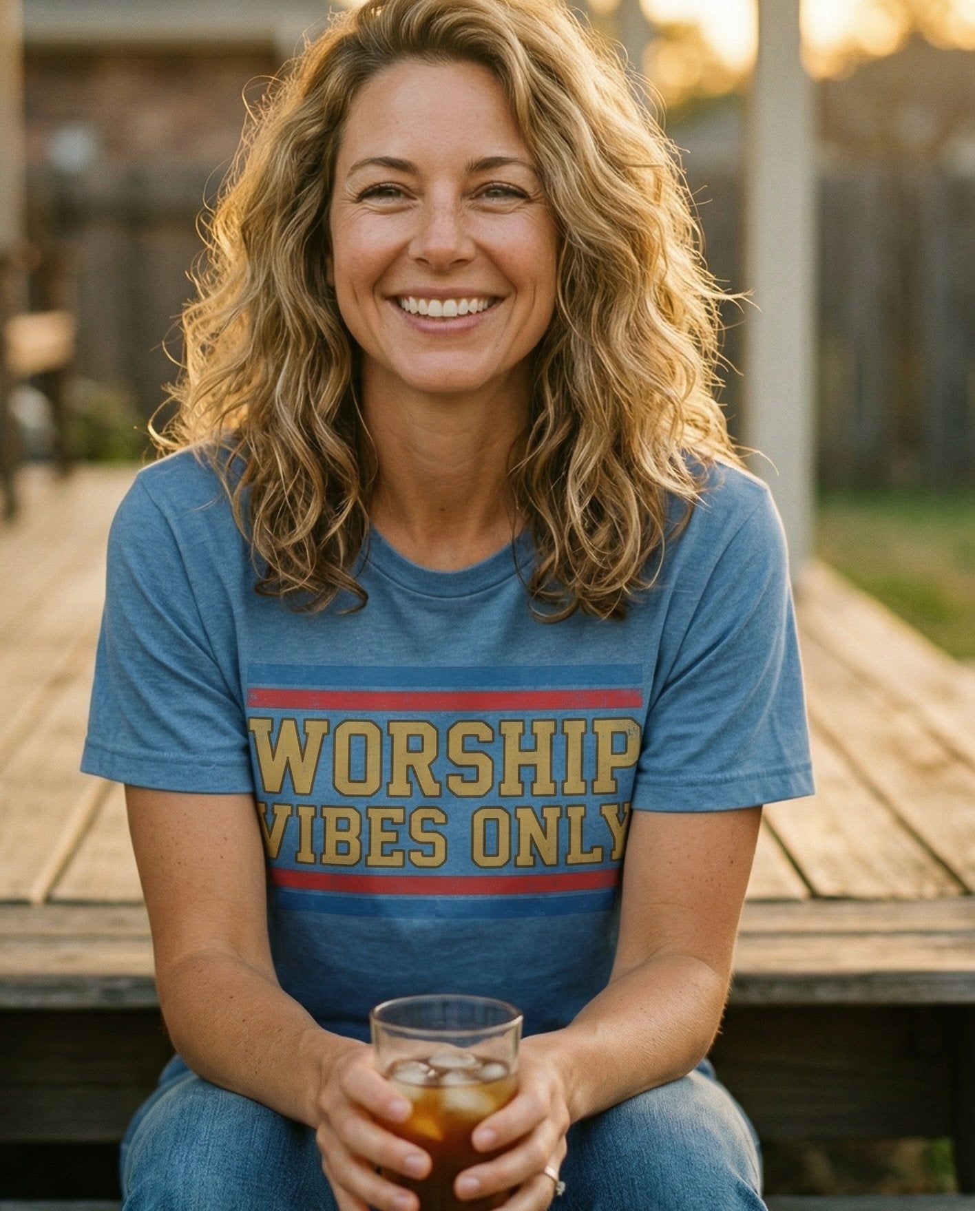 Worship Vibes Only – Blue Jean women's Christian tee, lifestyle photo in sunny porch – Vintage collegiate-style block lettering 'Worship Vibes Only' in gold  – She Wears Faith