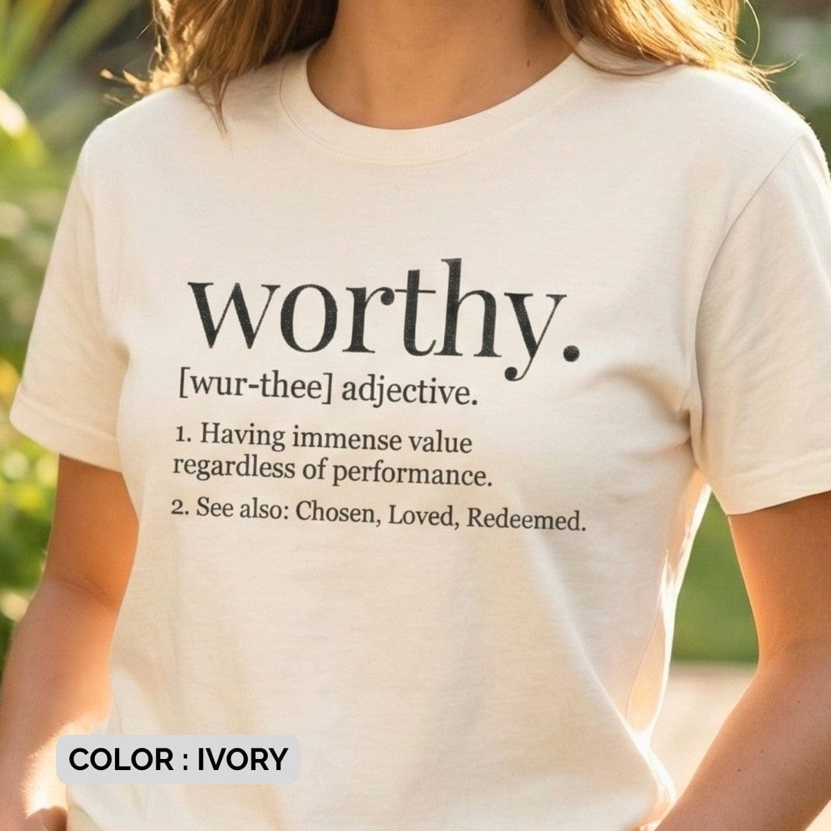 Woman outdoors wearing an Ivory Comfort Colors 1717 tshirt with a dictionary definition of "Worthy." Minimalist Christian women tee reminding believers they are chosen and loved, styled for US faith wear.