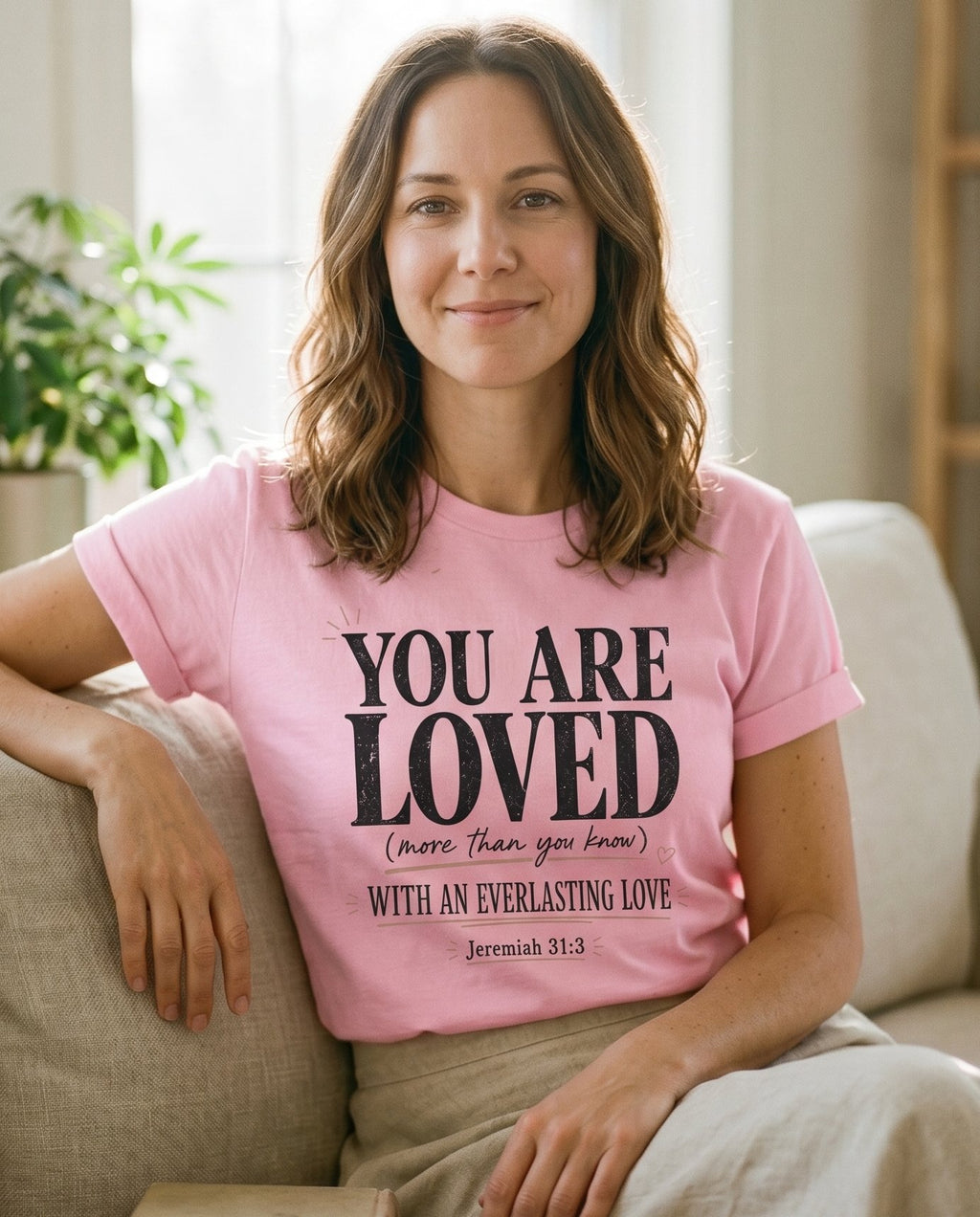 You Are Loved – Blossom women's Christian tee, lifestyle photo in cozy living room – You Are Loved beloved faith encouragement comfort floral lettering des – She Wears Faith